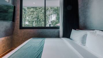 Un dormitorio con un gran ventanal, una cama y un televisor montado en la pared.