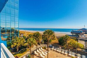 A beach view with palm trees, lounge chairs, and a boardwalk. - Yachtsman S402 Studio (Myrtle Beach)