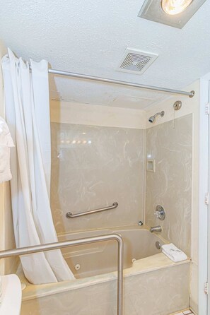 Un espace douche doté d’une porte en verre, d’une barre d’appui et d’un porte-serviettes.