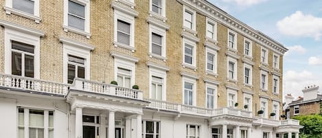 Un edificio residencial de varios pisos con fachada simétrica, ventanas de marco blanco y exterior de ladrillo.