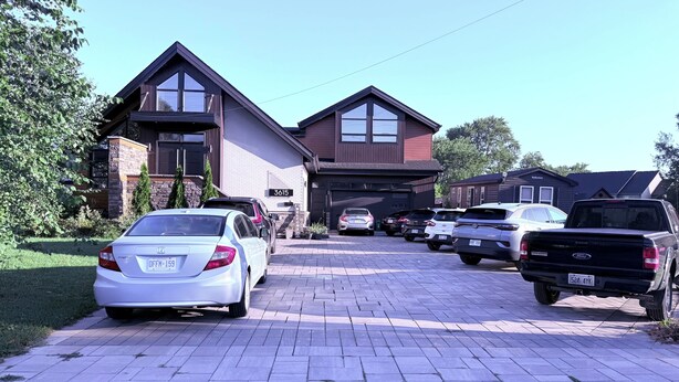 A residential driveway with parked cars and a house with a garage. - Superior Master Suite (Niagara Falls)