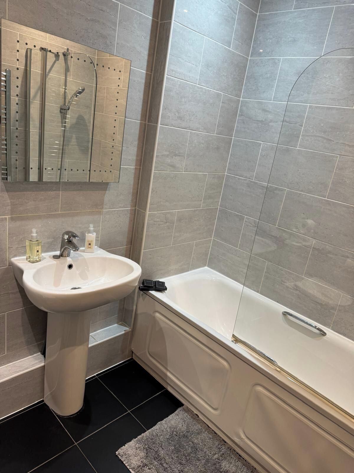 A bathroom with a white sink, a bathtub, and a shower enclosure.