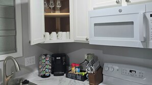 Een keuken met witte kasten, een inbouwmagnetron, een koffiezetapparaat en een koffiebar.