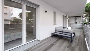 Un apartamento moderno con balcón, un sofá y una mesa de comedor.