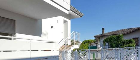A modern white building with a pool and a white fence.