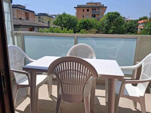 Ein Balkon mit Tisch und Stühlen, Blick auf Gebäude und ein klarer Himmel.