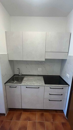 A compact kitchen with a single sink, a stove, and cabinets. - Holiday apartment with air conditioning and balcony (Bibione)