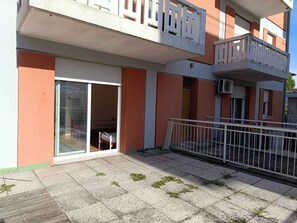 Ein modernes Mehrfamilienhaus mit Glastür, kleinem Balkon und gefliestem Patio.