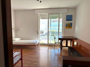 Ein Zimmer mit einem Bett, einem Tisch, einem Stuhl und Blick ins Freie.