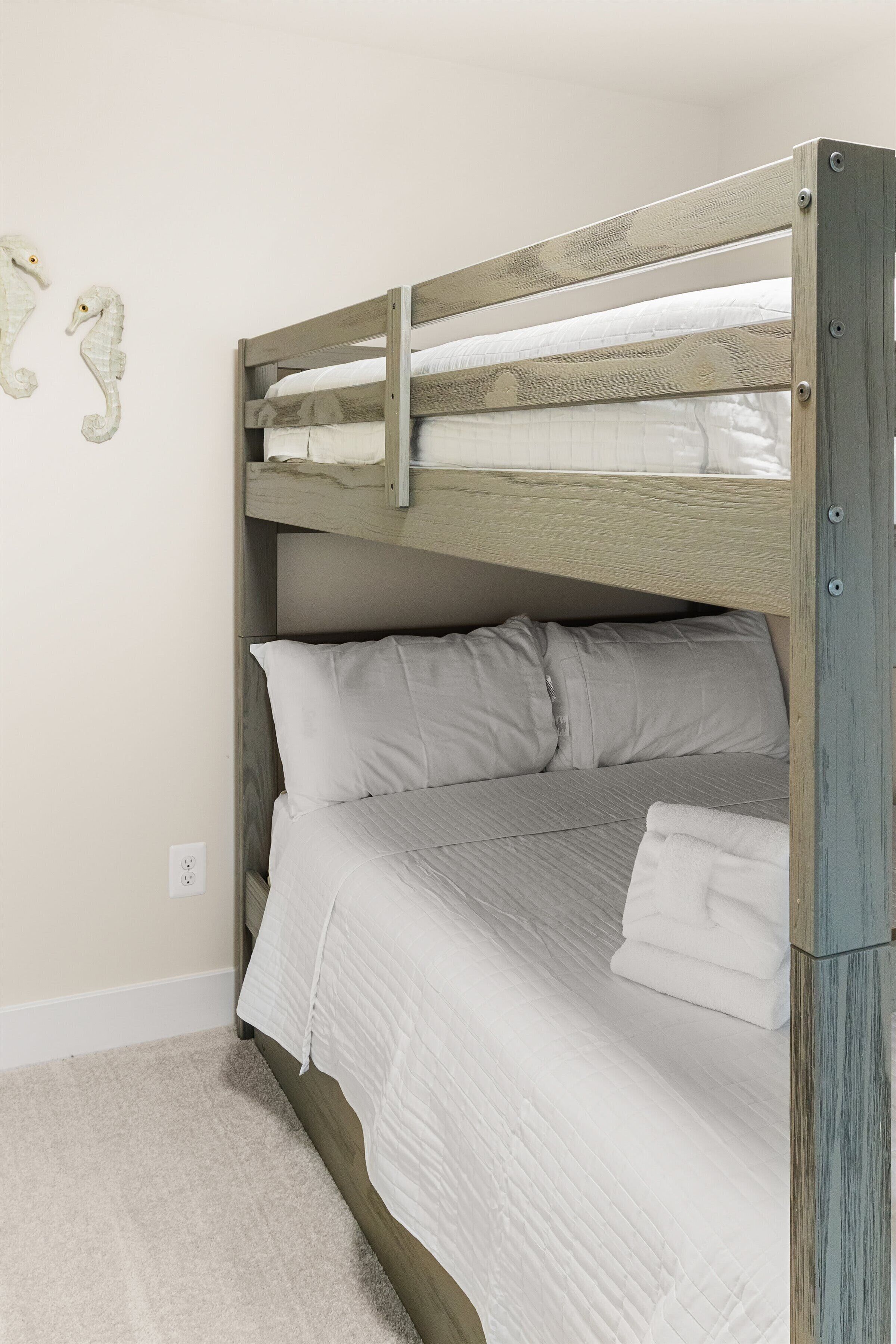 A bunk bed with white bedding and a wooden headboard.