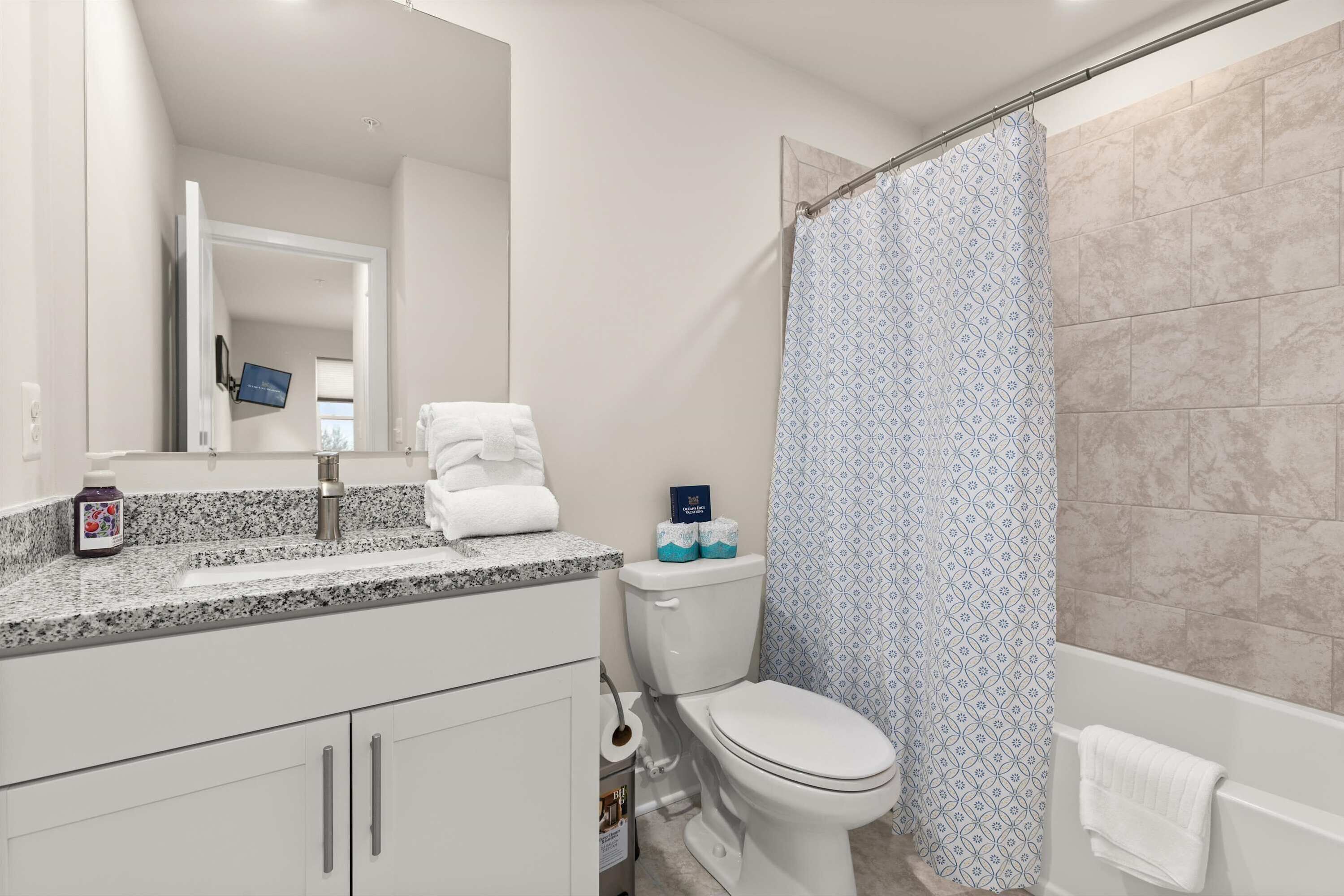 A bathroom with a toilet, a shower curtain, a sink with a mirror, and a towel rack.