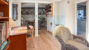 A cozy living room with a wooden floor, a bookshelf, a dining area with a table and chairs, and a wicker chair. - Lovely home in Nørreballe with WiFi (Nørreballe)