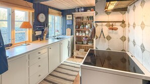 A kitchen with white cabinets, a stove, a sink, and a window with a view of trees. - Lovely home in Nørreballe with WiFi (Nørreballe)