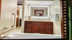 Une salle de bain avec un grand miroir, des meubles en bois, un lavabo et une baignoire.
