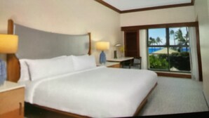 Une chambre d’hôtel avec un grand lit, un bureau et une fenêtre donnant sur des palmiers.