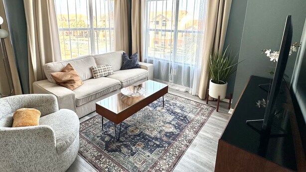 Een woonkamer met een bank, fauteuil, salontafel en een televisie.