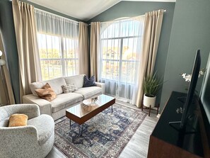 Un salon comprenant un canapé, un fauteuil, une table basse et un téléviseur.