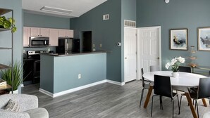 Een moderne keuken met een centraal eiland, een zithoek met een witte tafel en stoelen, en een plafondventilator.