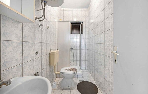 Een badkamer met een badkuip, toilet en douche.