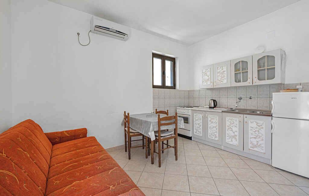 Une cuisine de taille réduite avec des meubles blancs, une table à manger avec des chaises et un canapé rouge.