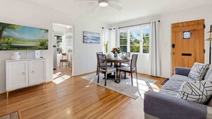 Ein geräumiges Wohnzimmer mit Essbereich, Deckenventilator und Blick durch große Fenster.
