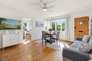 Ein geräumiges Wohnzimmer mit Essbereich, Deckenventilator und Blick durch große Fenster.