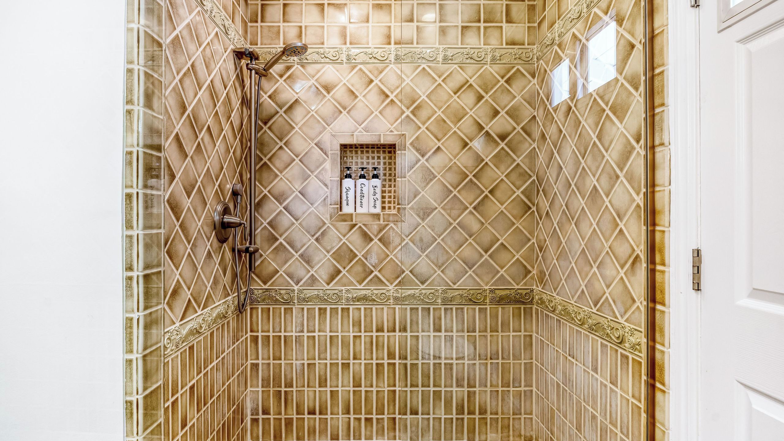 Un baño con ducha, tocador con espejo y una ventana pequeña.