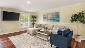 A living room with a sofa, a coffee table, a TV, and artwork on the wall. - Twilight Terrace by Avantstay West Hills Retreat Hot Tub, BBQ + EV Charger, Near Malibu (West Hills)