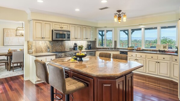 A spacious kitchen with a central island, large windows, and a view of the outdoors. - Twilight Terrace by Avantstay West Hills Retreat Hot Tub, BBQ + EV Charger, Near Malibu (West Hills)