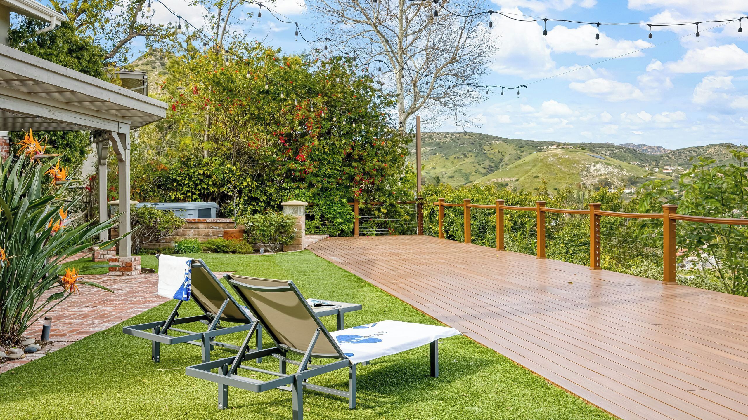 Een terras met buitenmeubilair, een pergola en uitzicht op heuvels.