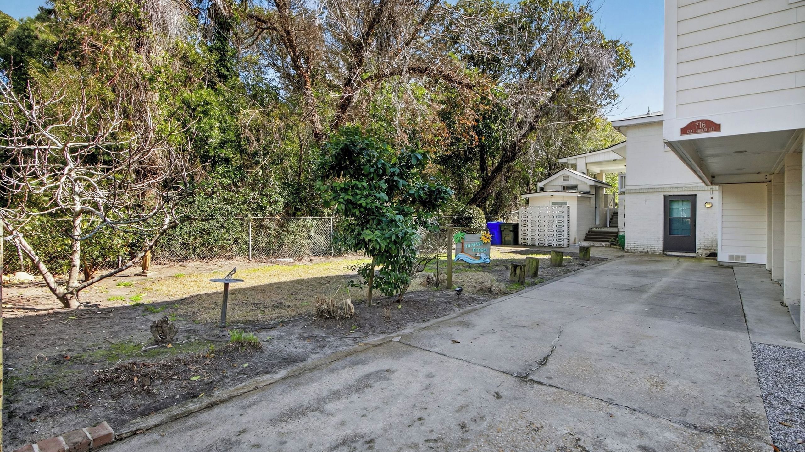 A residential property with a paved driveway, a fenced yard, and a house with a visible front door and garage.