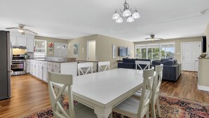 Une cuisine moderne avec des meubles blancs, une table à manger et un ventilateur de plafond.