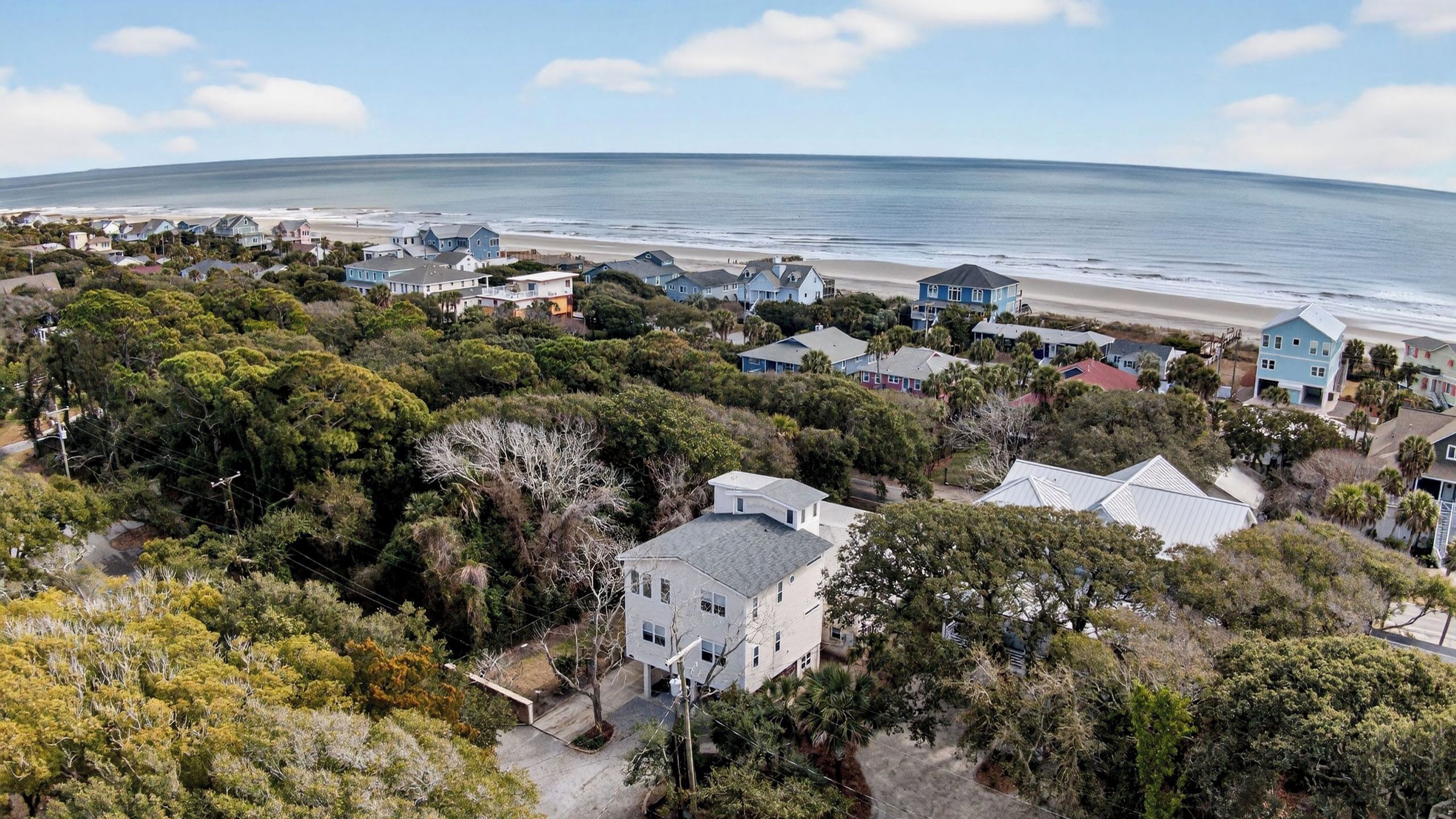 A coastal residential area with houses, a beach, and a lighthouse.