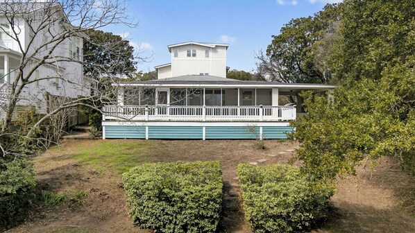 A two-story house with a porch, a fenced yard, and a small garden.
