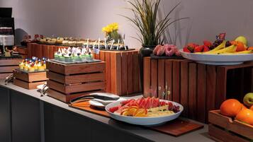 Disposição de buffet com diversos alimentos e uma planta decorativa.