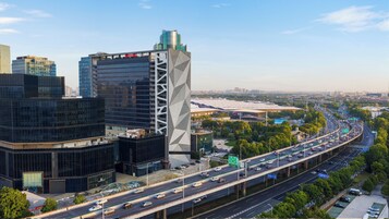 A modern urban landscape with high-rise buildings, a multi-level highway, and a large stadium.