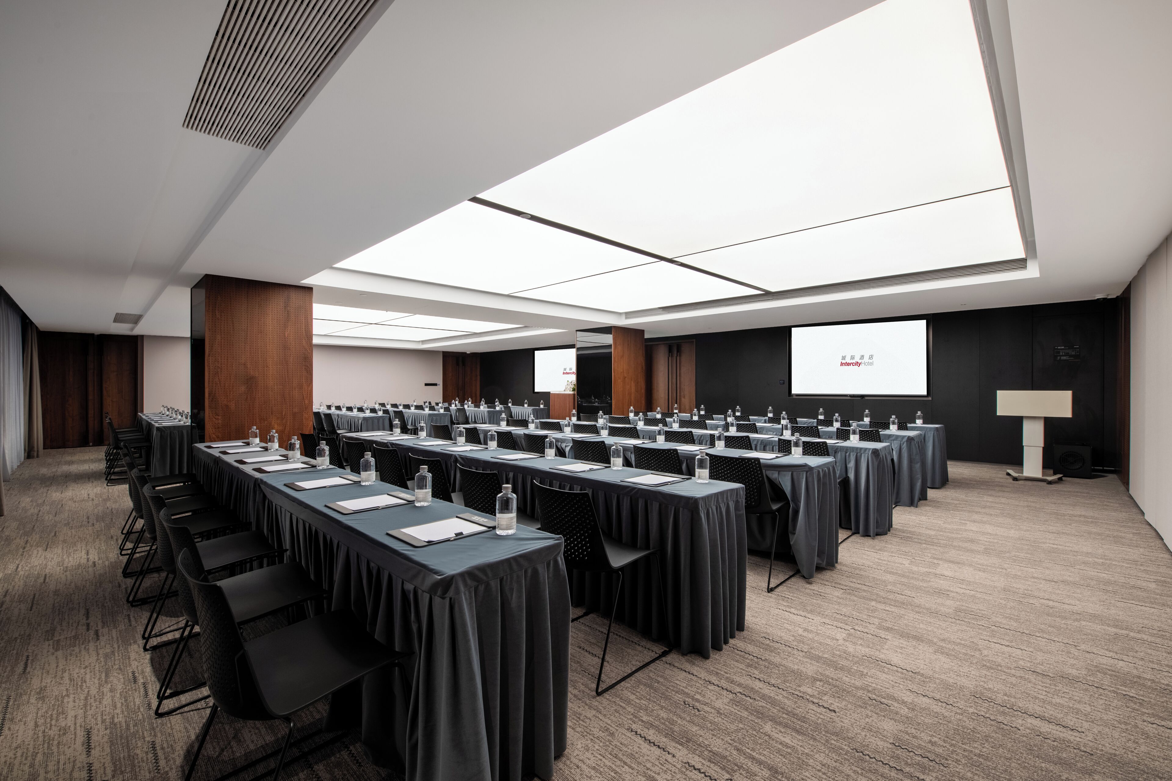 A conference room with long tables, chairs, and a projector screen.