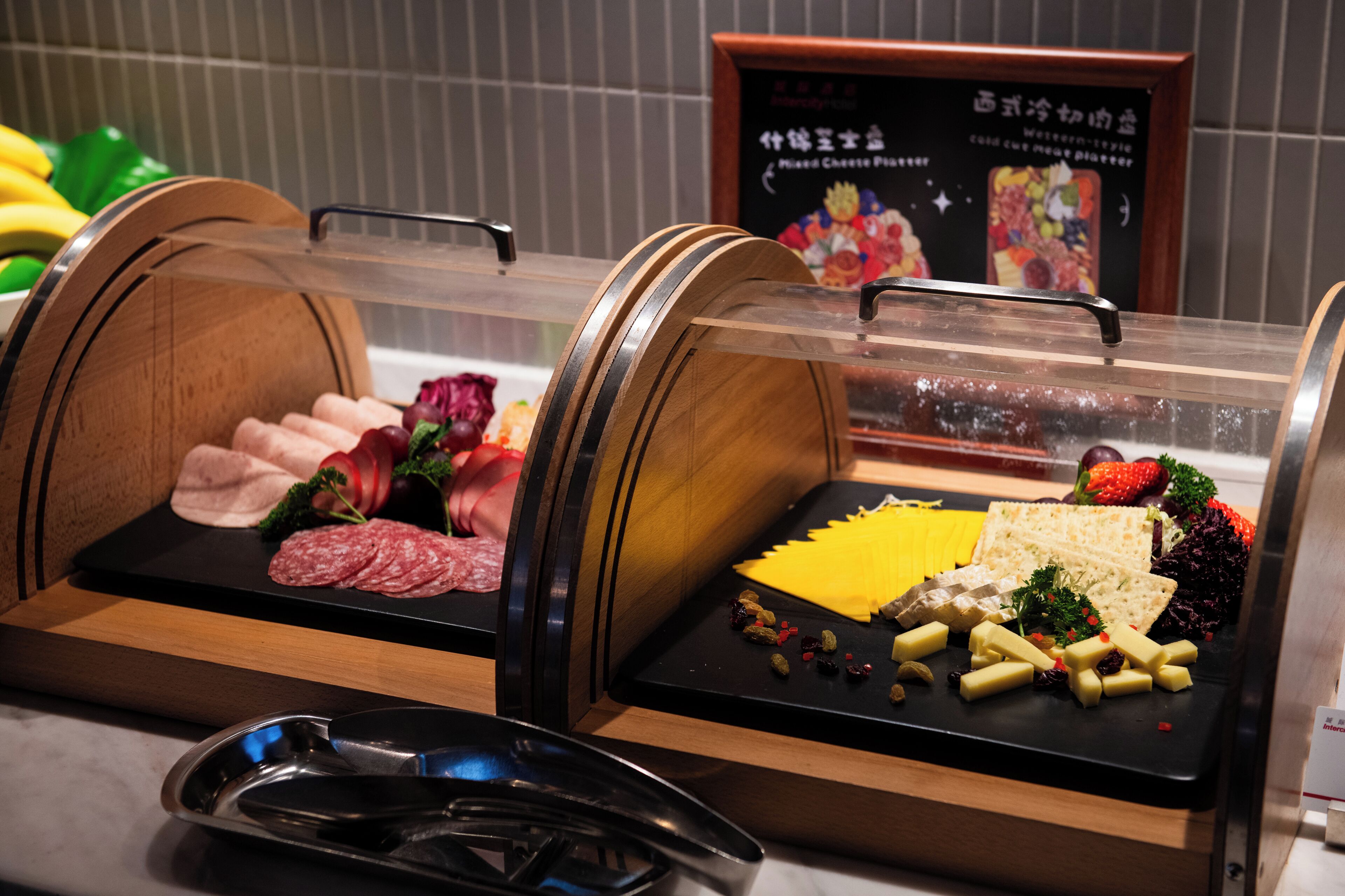 A food display with various cheeses, meats, and fruits.