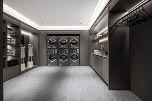 A modern laundry room with a built-in washer and dryer, a drying rack, and a small shelf with toiletries.