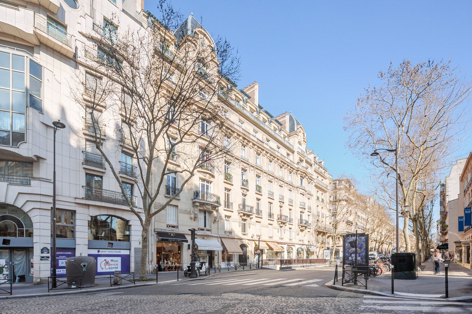 Vista de una calle con un edificio histórico de varios pisos, grandes ventanales y balcones.