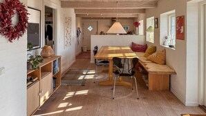 A cozy, well-lit dining area with a wooden table and chairs, a bench with cushions, and a decorative wreath on the wall. - 2 bedroom nice home in Fanø (Fanø)