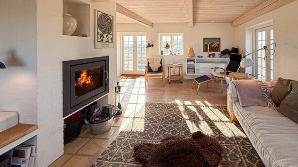 A cozy living room with a fireplace, wooden furniture, and a view of the outdoors. - 2 bedroom nice home in Fanø (Fanø)