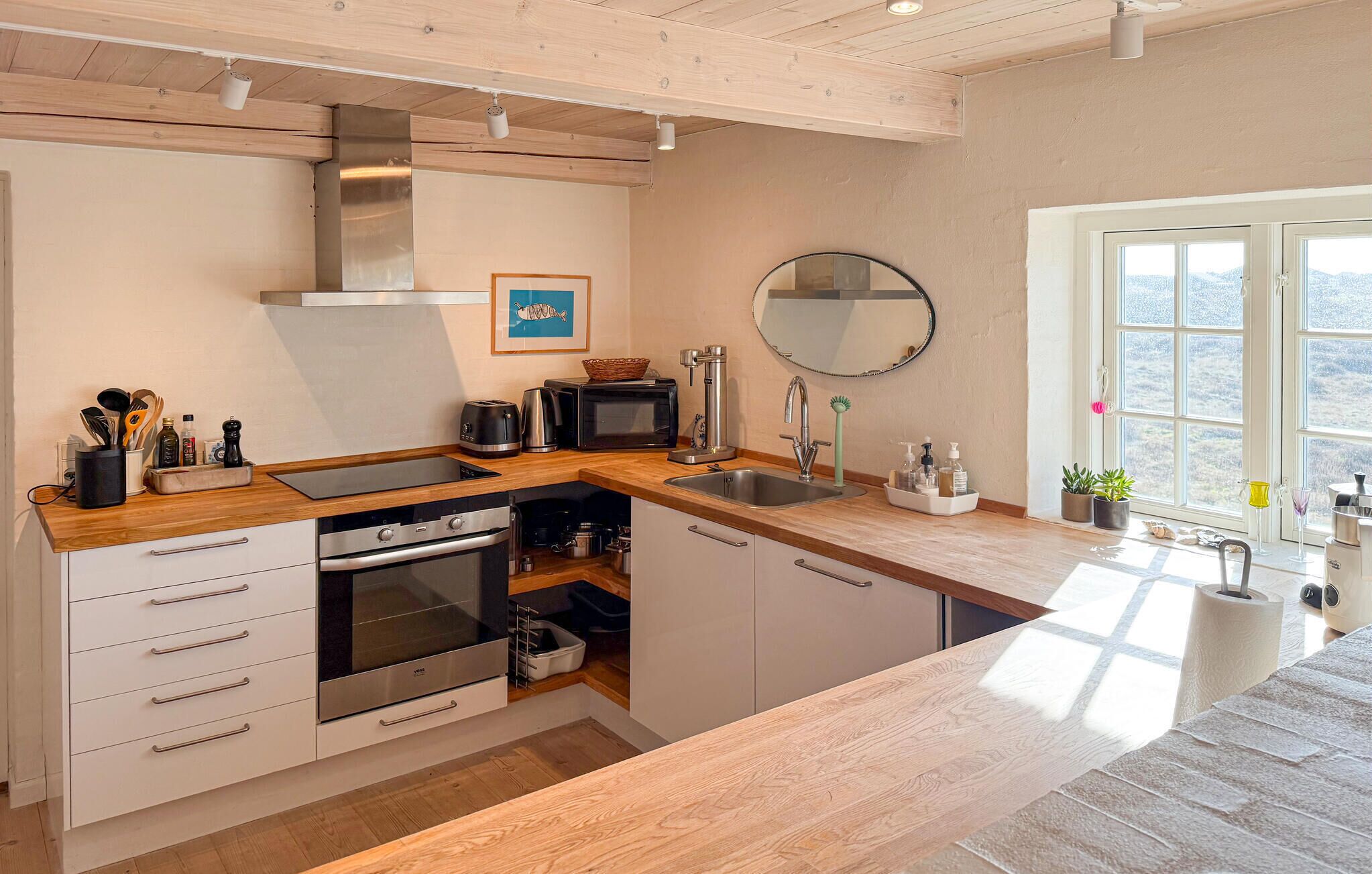 A modern kitchen with a wooden countertop, stainless steel appliances, a large window, and a view of the outdoors.