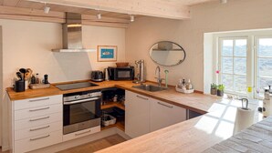 A modern kitchen with a wooden countertop, stainless steel appliances, a large window, and a view of the outdoors. - 2 bedroom nice home in Fanø (Fanø)