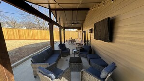 Une terrasse extérieure avec des meubles en osier et un ventilateur de plafond.