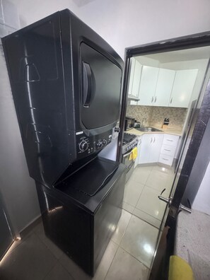 A compact kitchen with a black stove, a microwave, and a sink. - First floor  2-bedroom apartment with AC in vibrant Moca (Moca)