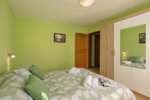 A bedroom with a bed, pillows, a door, and a mirror. - Magda 2 Apt with Panoramic Sea View, Plomin, Croatia (Plomin)