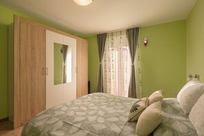 Ein Schlafzimmer mit Bett, Kleiderschrank und Vorhängen.