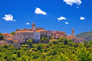 A historic town with a prominent church tower, surrounded by lush greenery and traditional buildings. - Magda 1 Apt with Panoramic Sea View, Plomin, Croatia (Plomin)