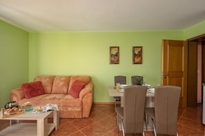 A living room with a sofa, coffee table, and dining area with chairs and a table. - Magda 1 Apt with Panoramic Sea View, Plomin, Croatia (Plomin)